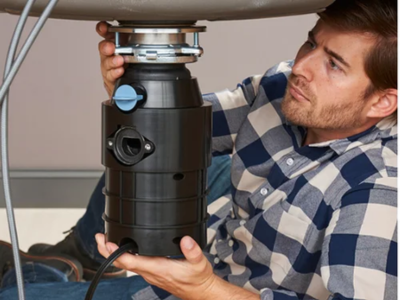 Professional plumber performing a garbage disposals install in Fort Lauderdale, carefully mounting a new black disposal unit to the sink flange.