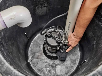 A professional emergency plumber in Fort Lauderdale inspecting and testing the float switch on a newly installed sump pump in a residential basin.